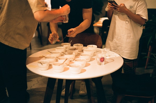 a group of people standing around a table with cups on it