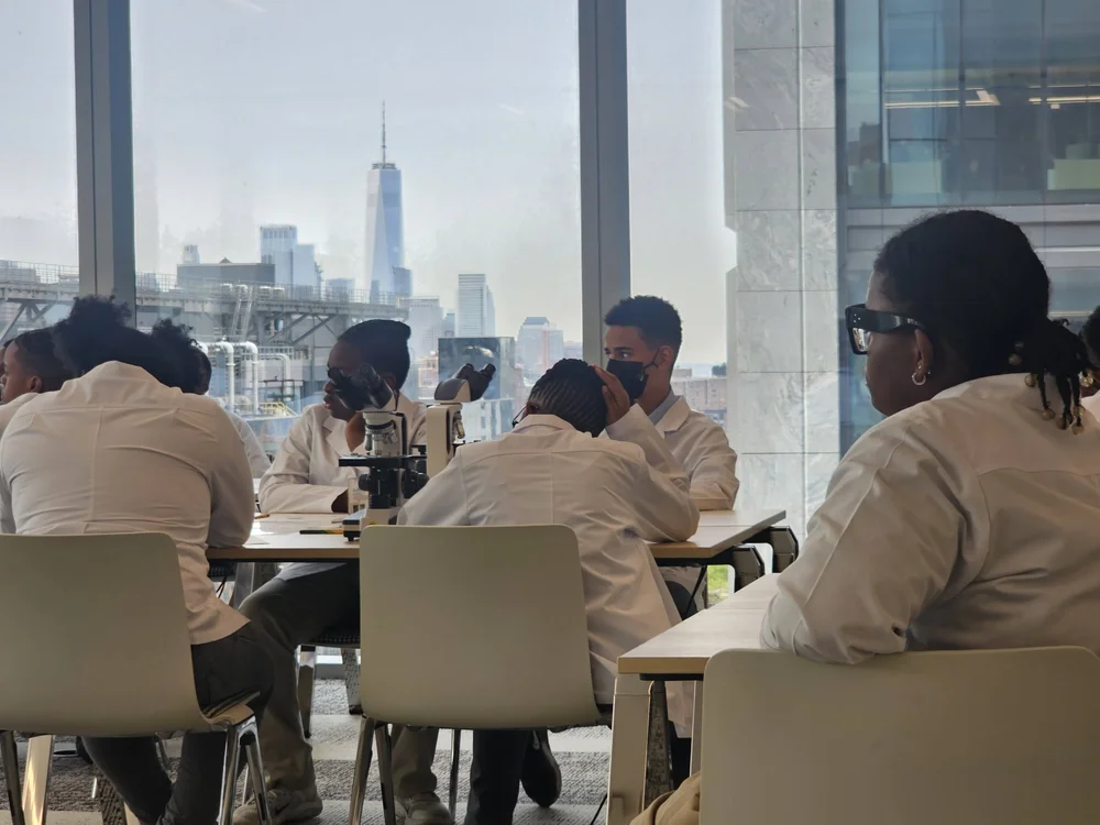 Students in lab coats using microscopes in a science classroom