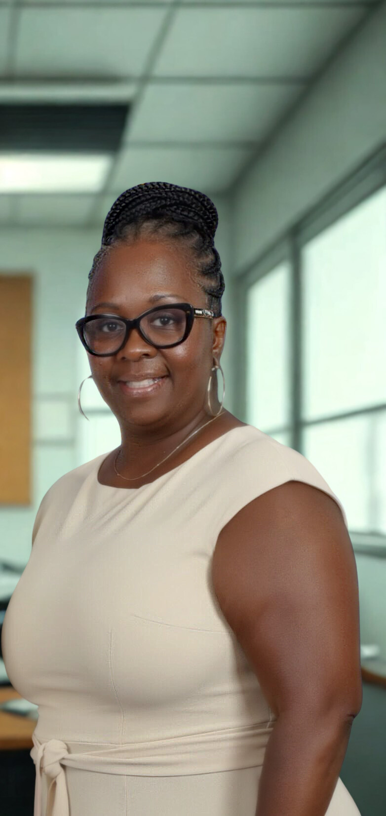 Principal smiling in school office wearing glasses and beige dress