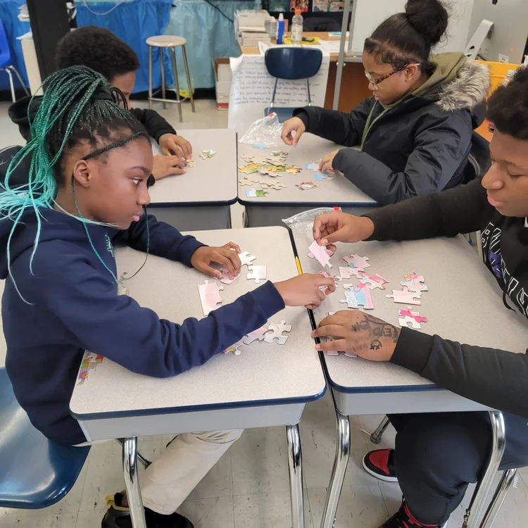 Students working together on jigsaw puzzles at classroom desks