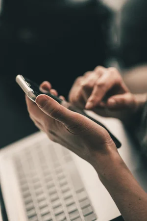 Person using a smartphone near a laptop keyboard