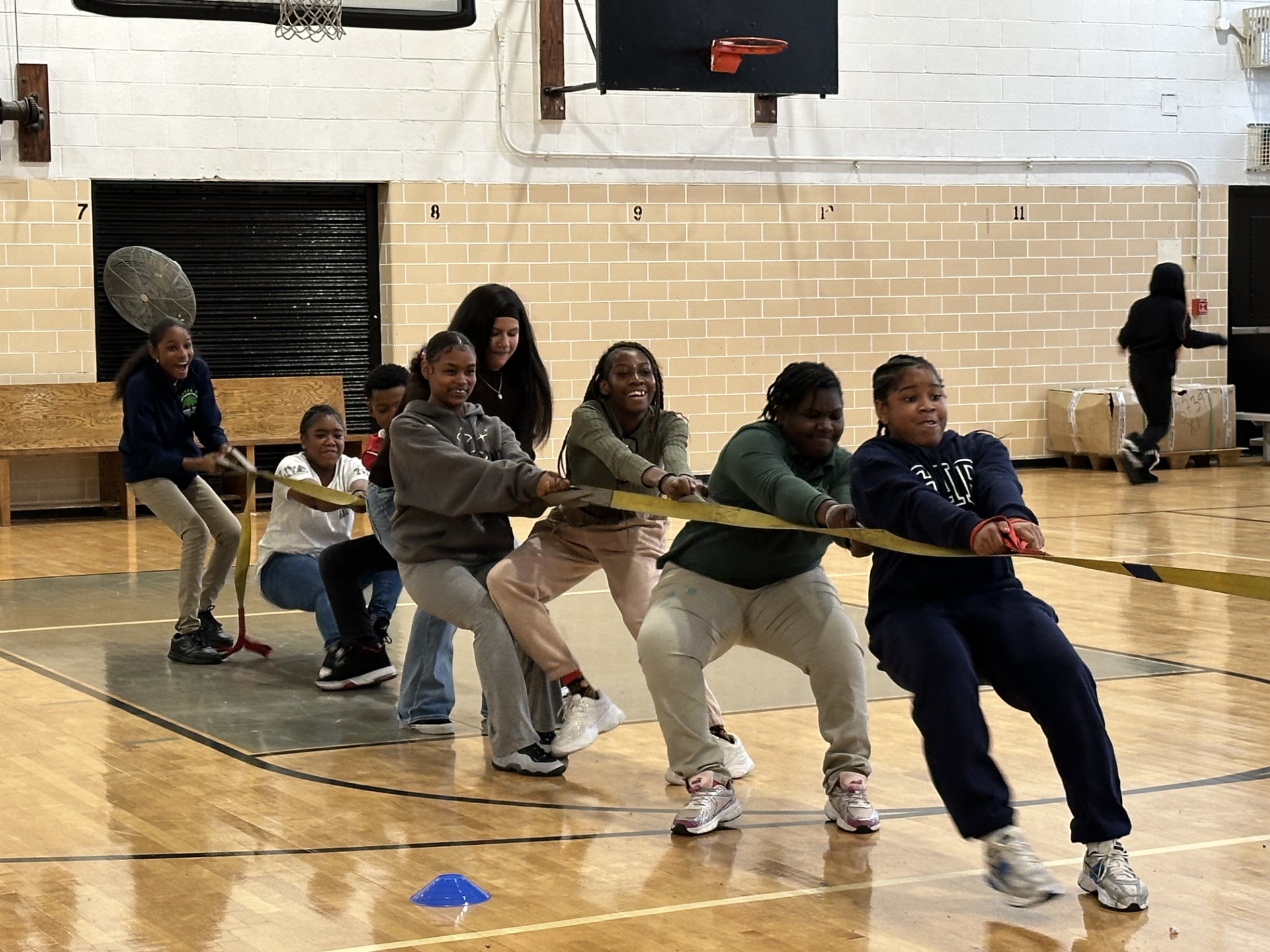 Students playing tug of war together in school gymnasium