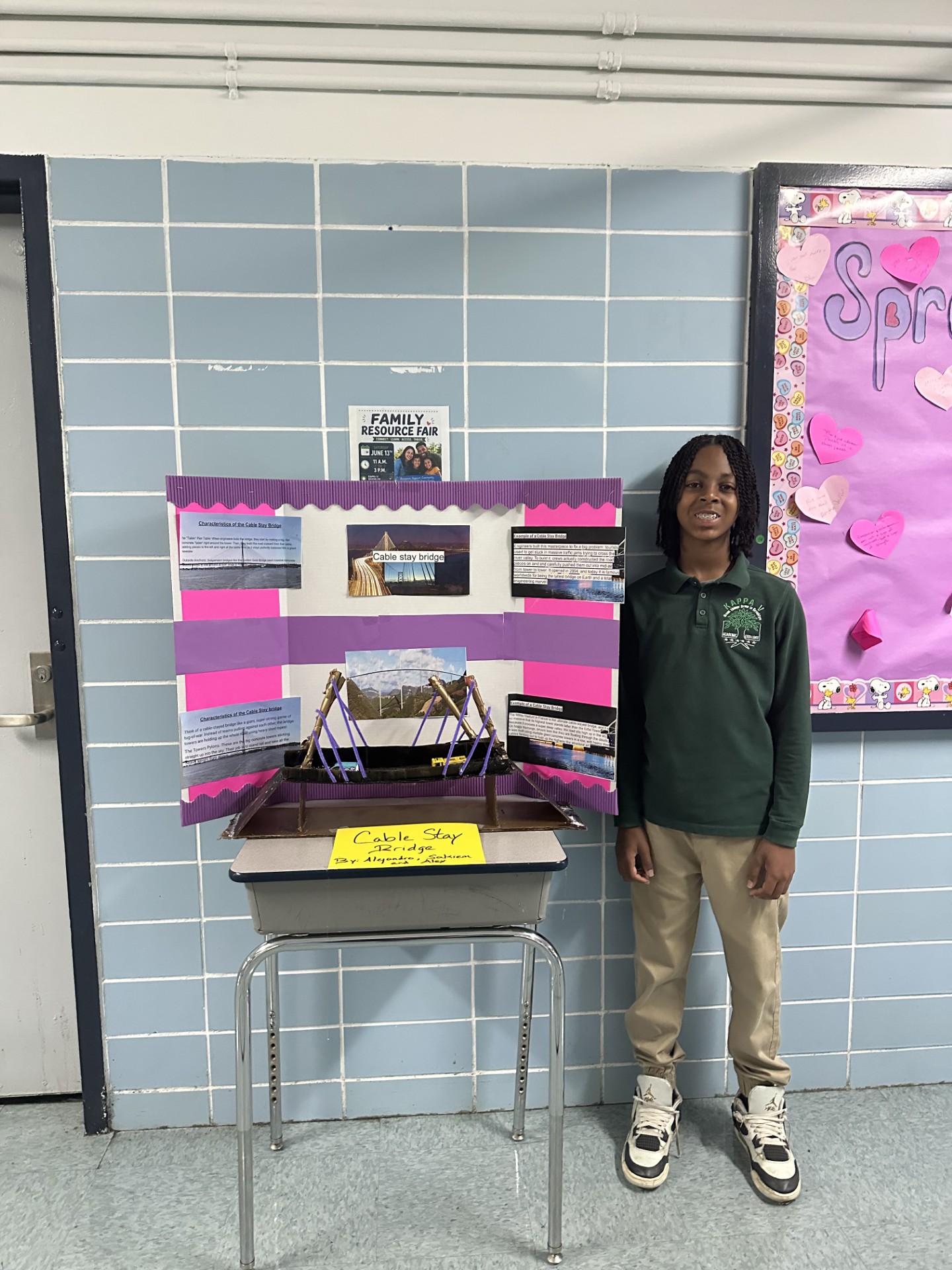 Student stands beside cable stay bridge project display board