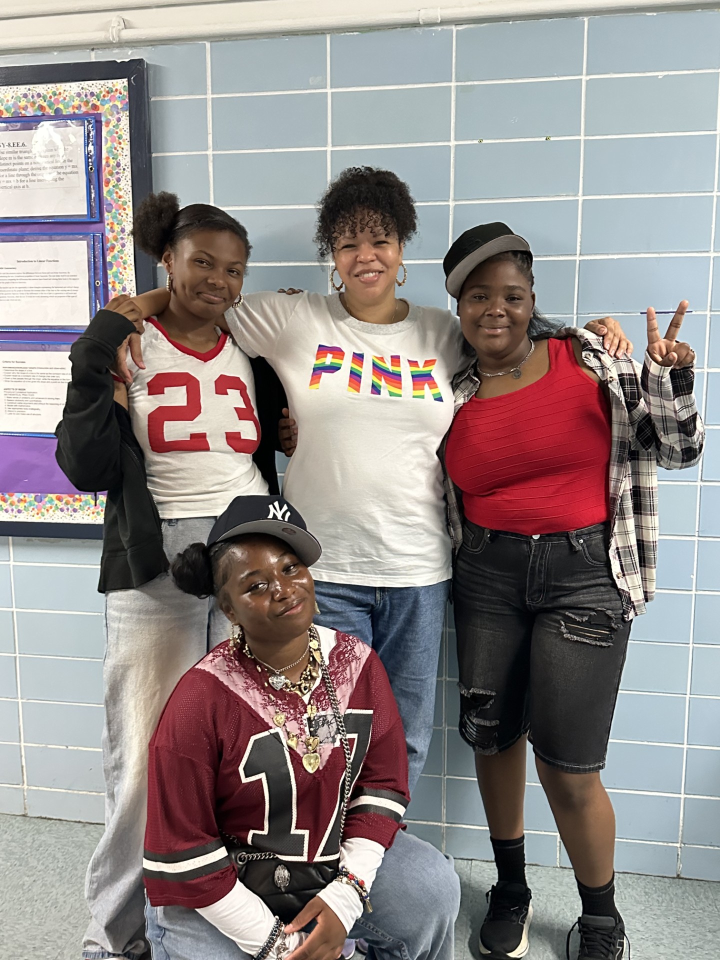 Four students posing together in school hallway wearing jerseys