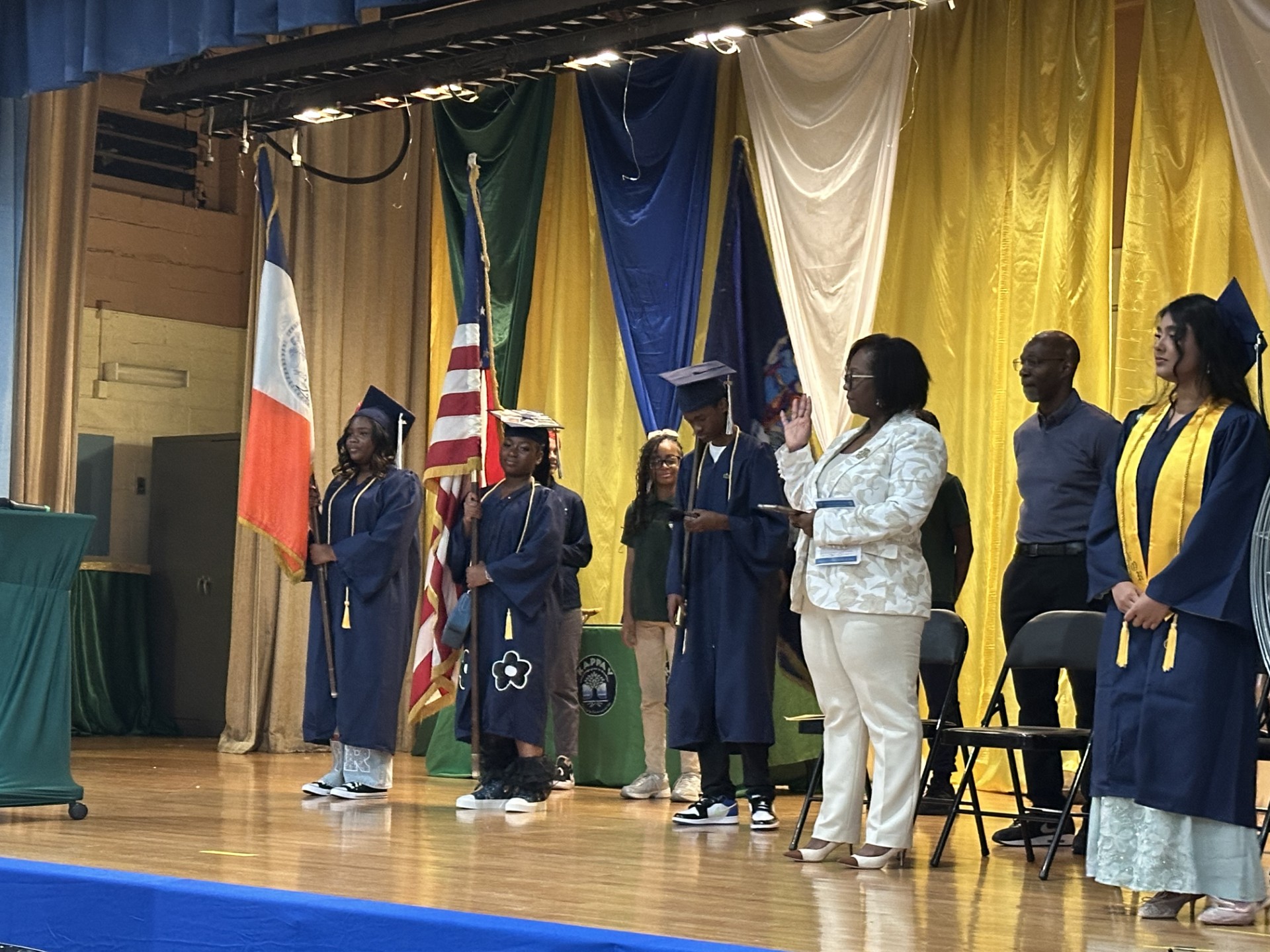 Students in graduation gowns on stage during school graduation ceremony
