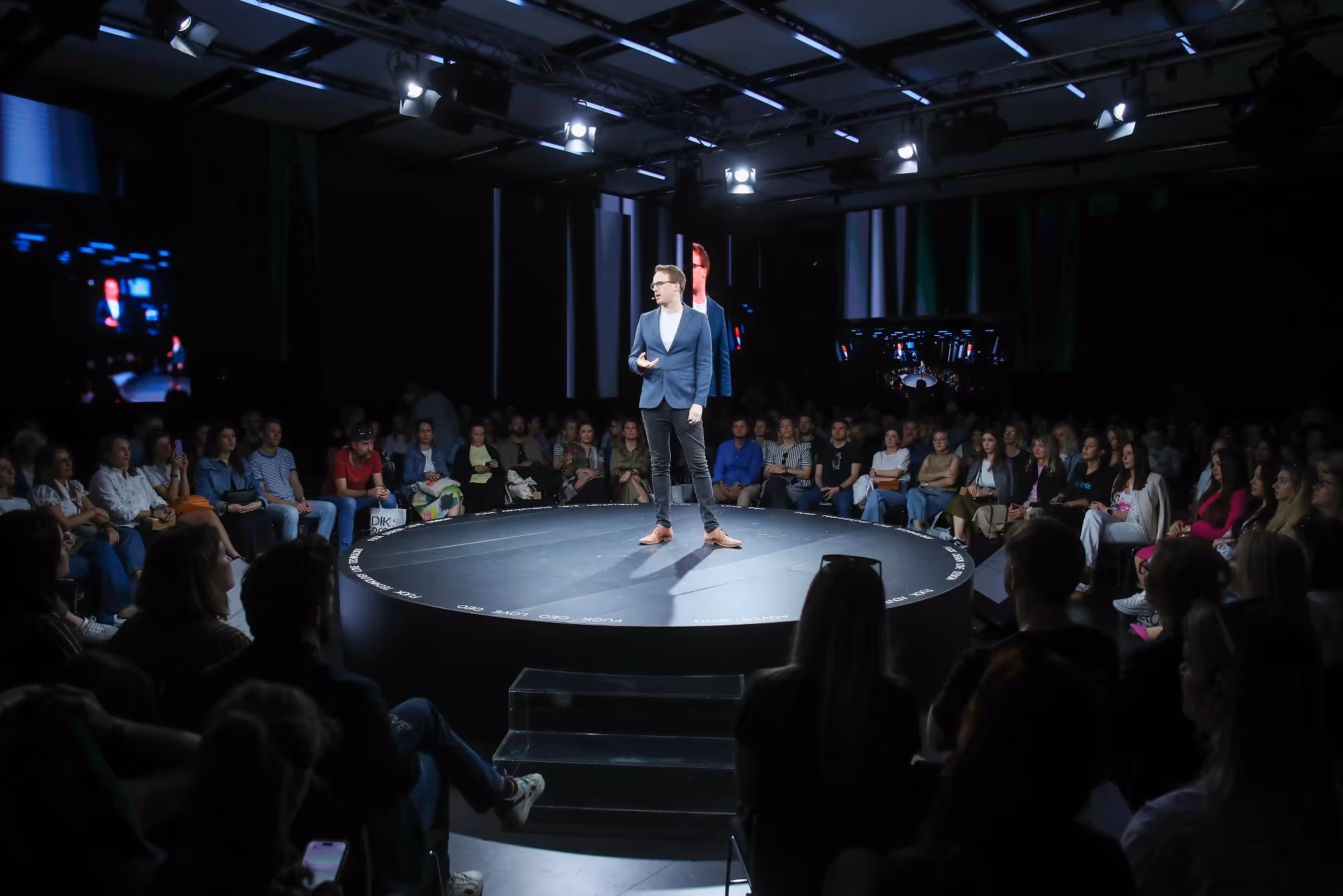 Alex Partridge in a blue suit and white t shirt talking about ADHD a conference