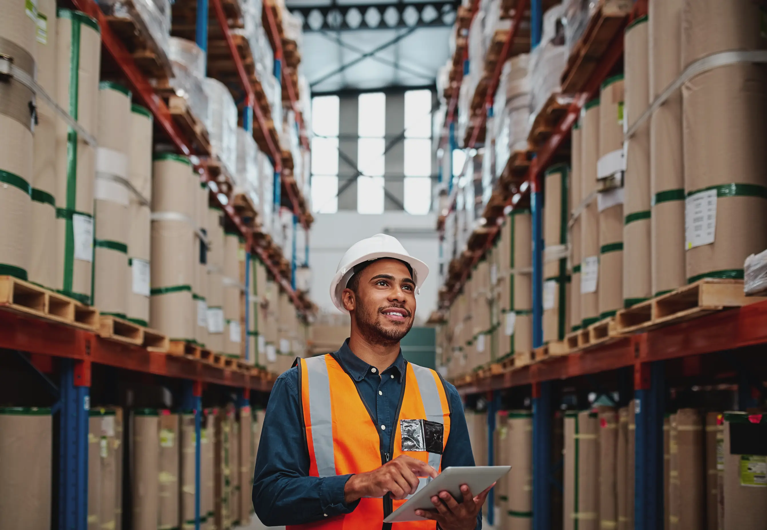 travailleur dans une usine avec un casque de protection et un gilet orange