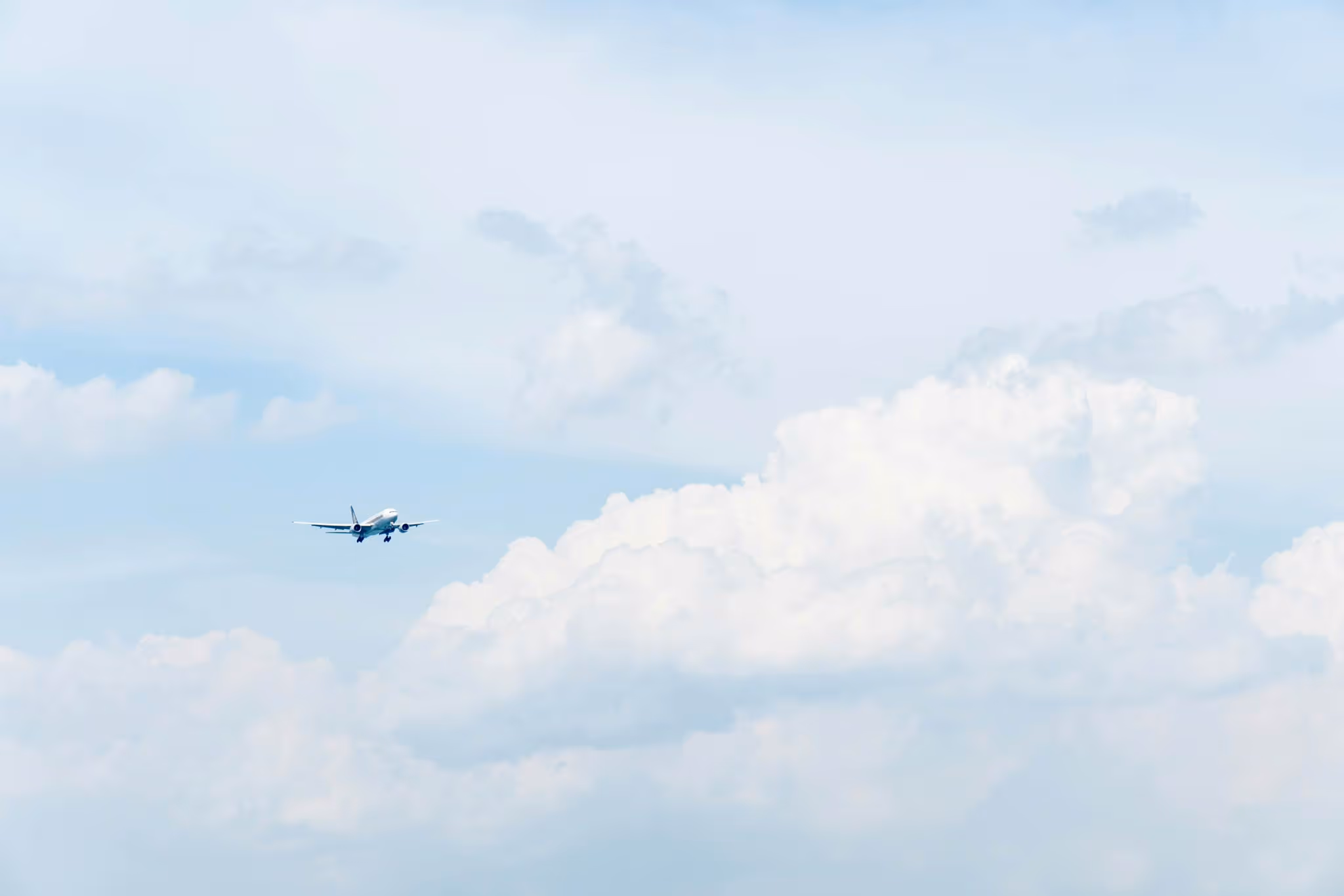 Passenger airplane flying in a partly cloudy blue sky.