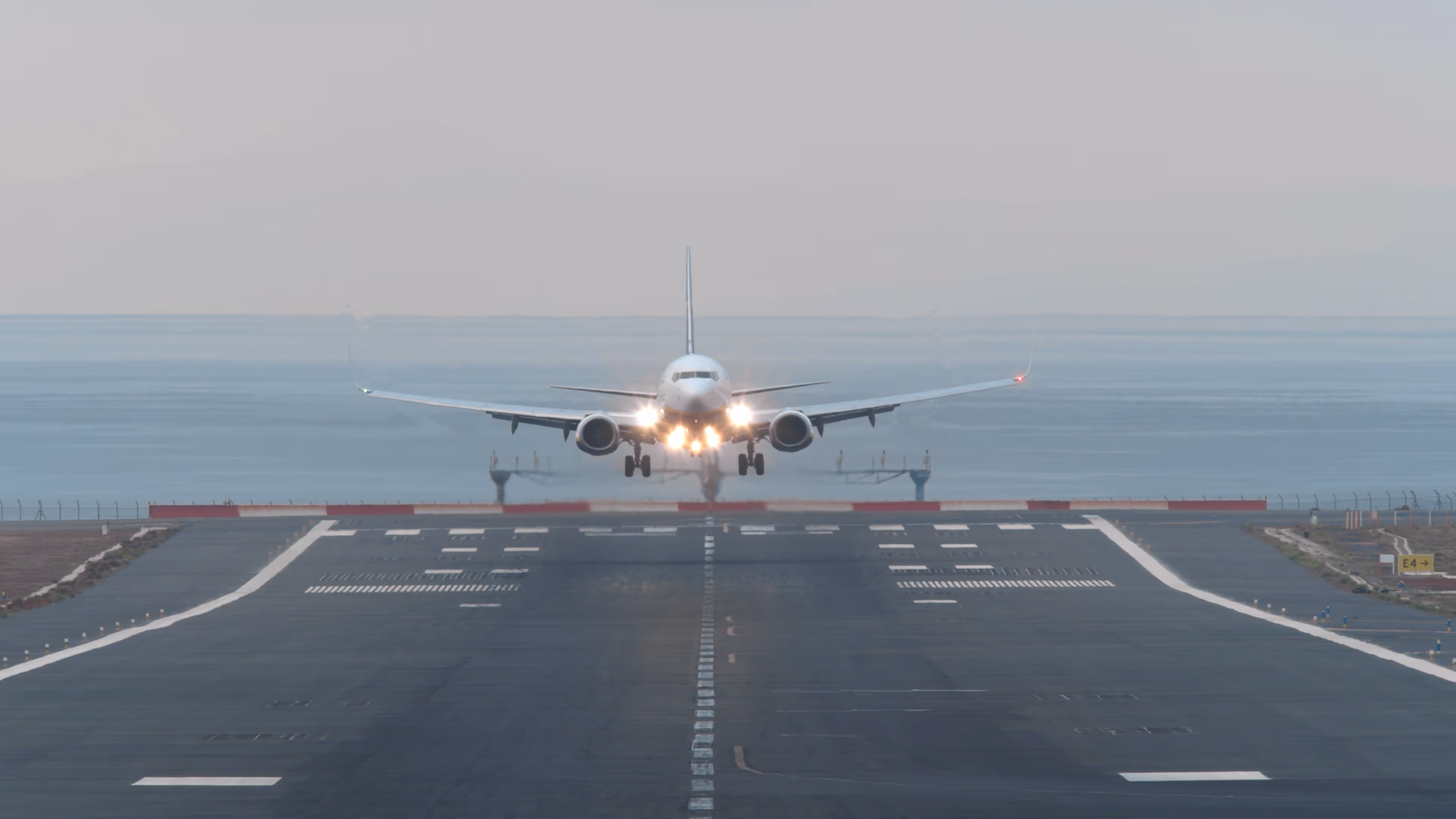 Commercial airplane approaching a runway for landing with landing lights on.