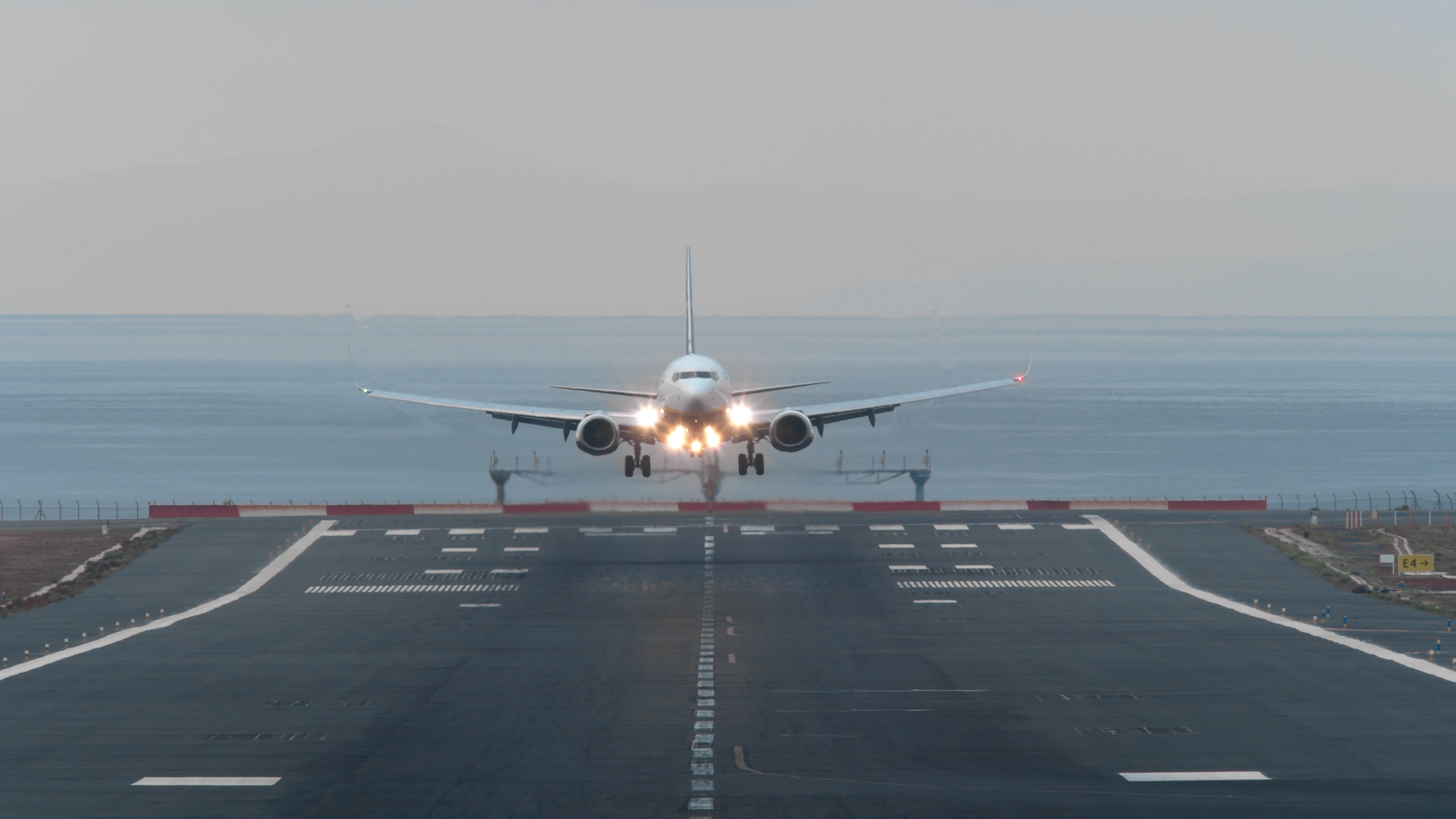 Commercial airplane approaching a runway for landing with landing lights on.