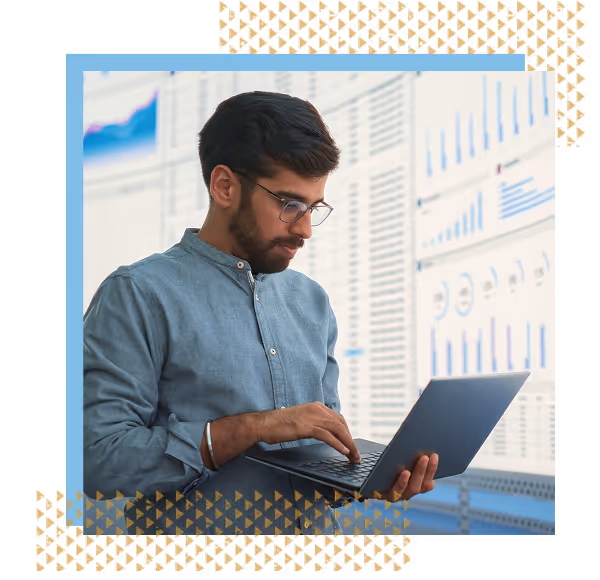 a data analyst examining his laptop in front of a wall of information