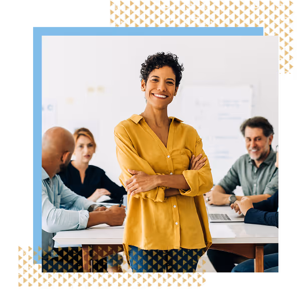 a confident female manager smiling for the camera in front of a team meeting
