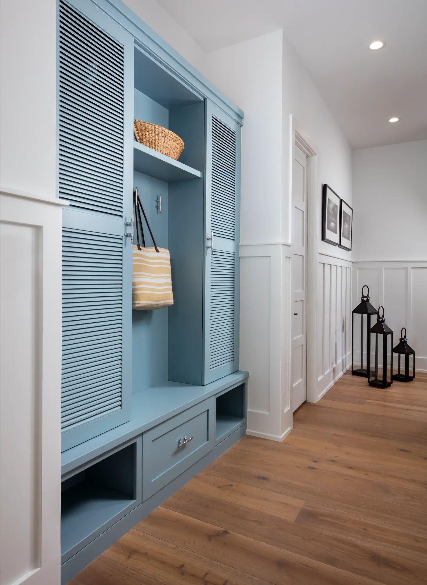 A blue cabinet with open shelves holding a striped bag and wicker basket in a hallway.