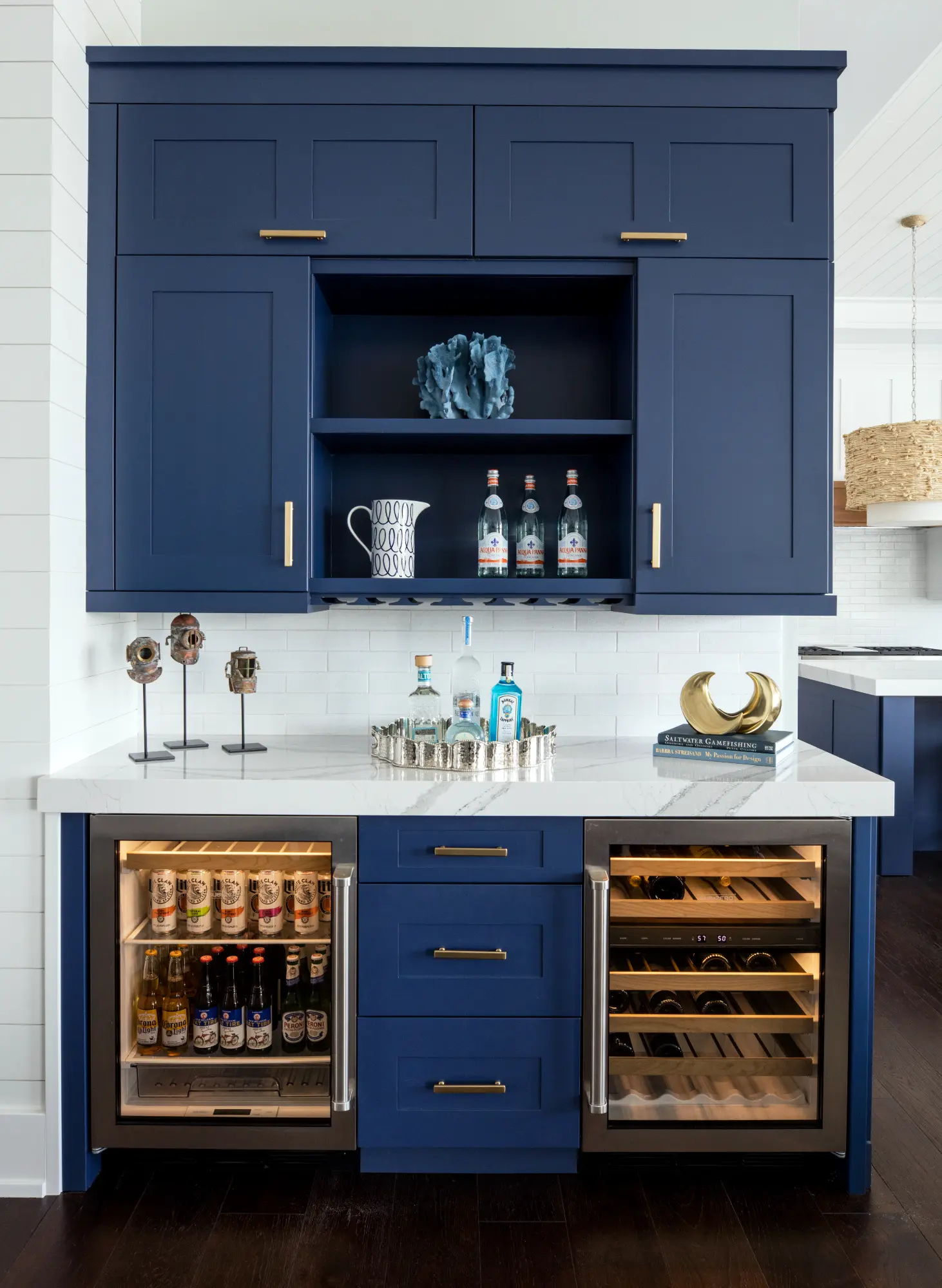 A blue cabinet with a white countertop holds beverages and decorations, including bottles and a pitcher.