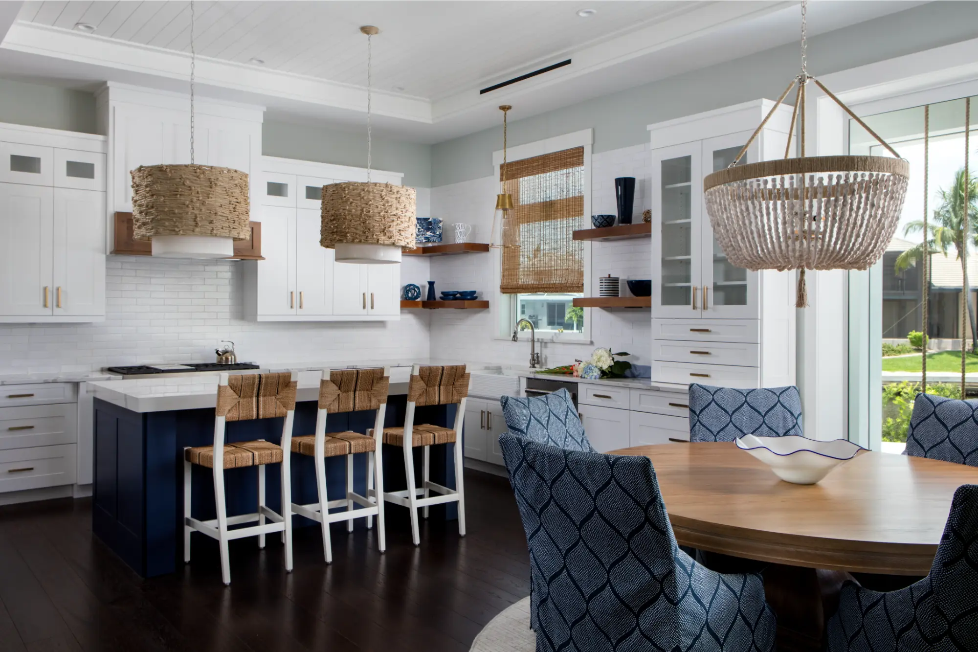 A modern kitchen with white cabinets, a wooden table, and wicker light fixtures above the island.