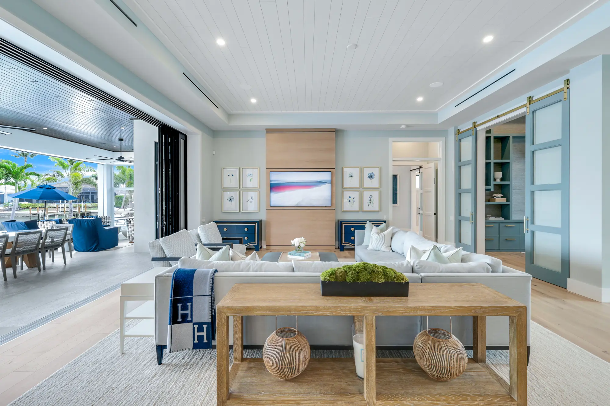 A spacious living room with a large sofa faces a flat-screen TV. Sliding doors open to a patio.