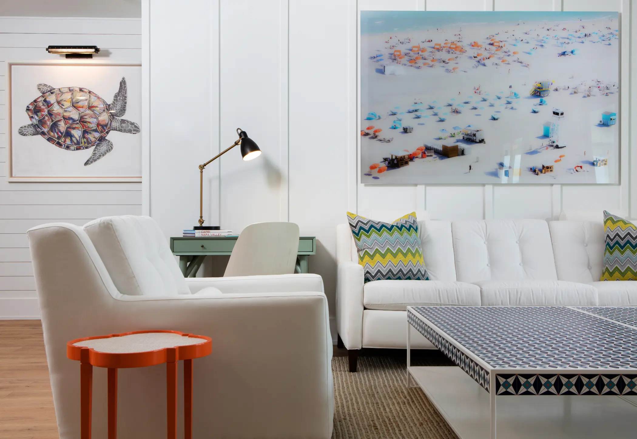 A modern living room with white furniture, a colorful side table, and a large wall painting.