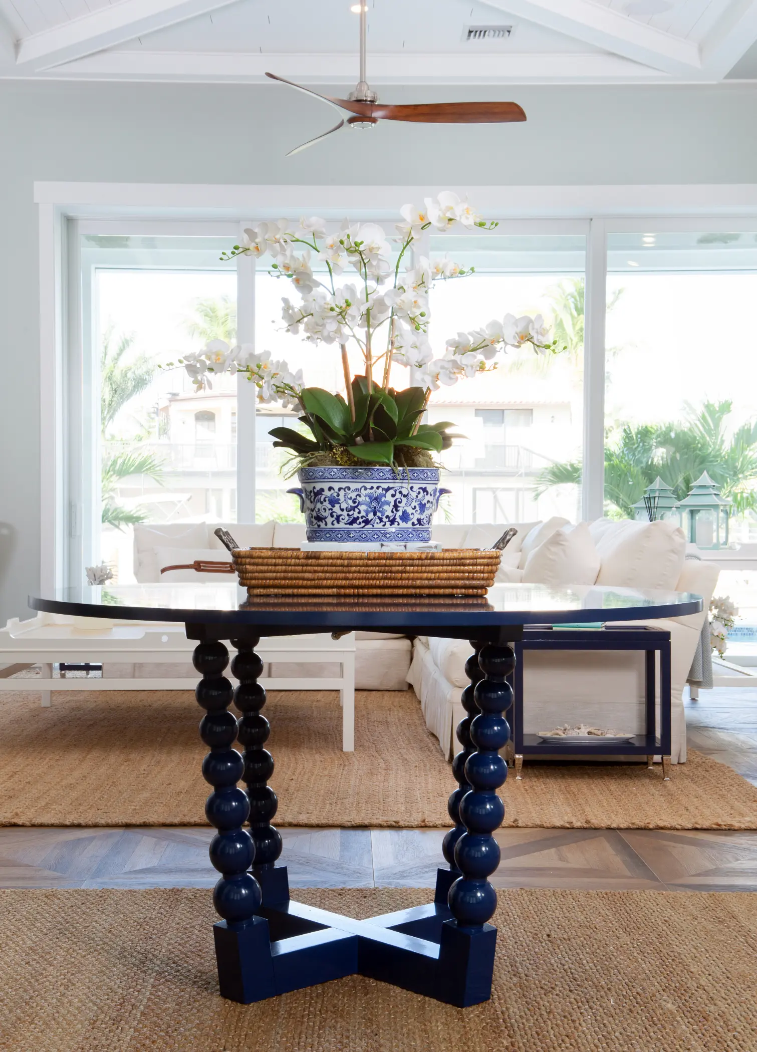 A potted orchid sits on a blue and white table in a bright living room.