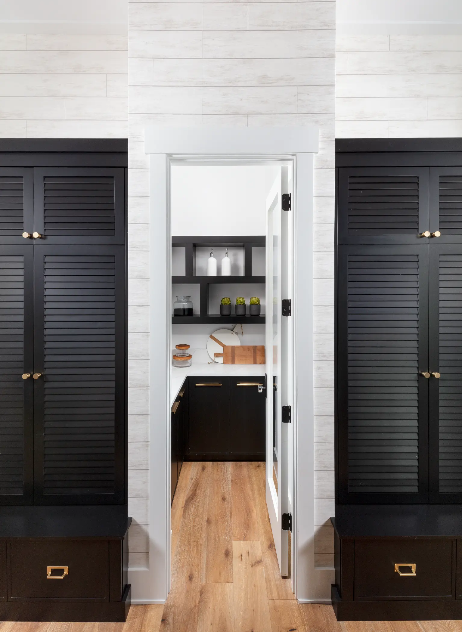 Open door reveals a small pantry with shelves and a countertop with cutting board.