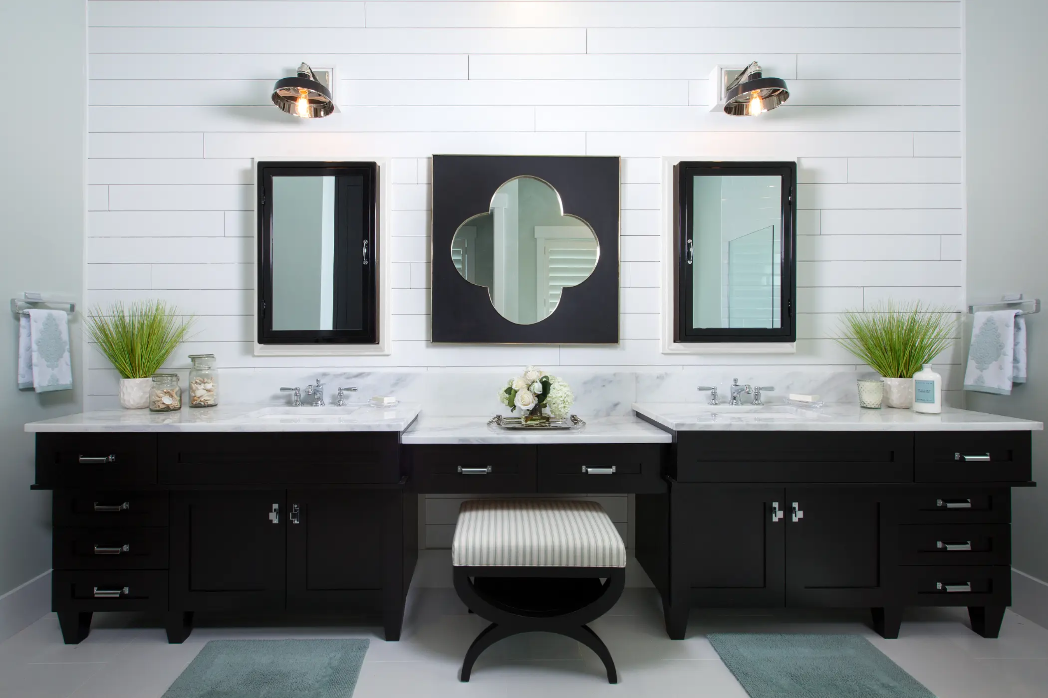 A modern bathroom with two sinks, two mirrors, and a central geometric wall mirror.