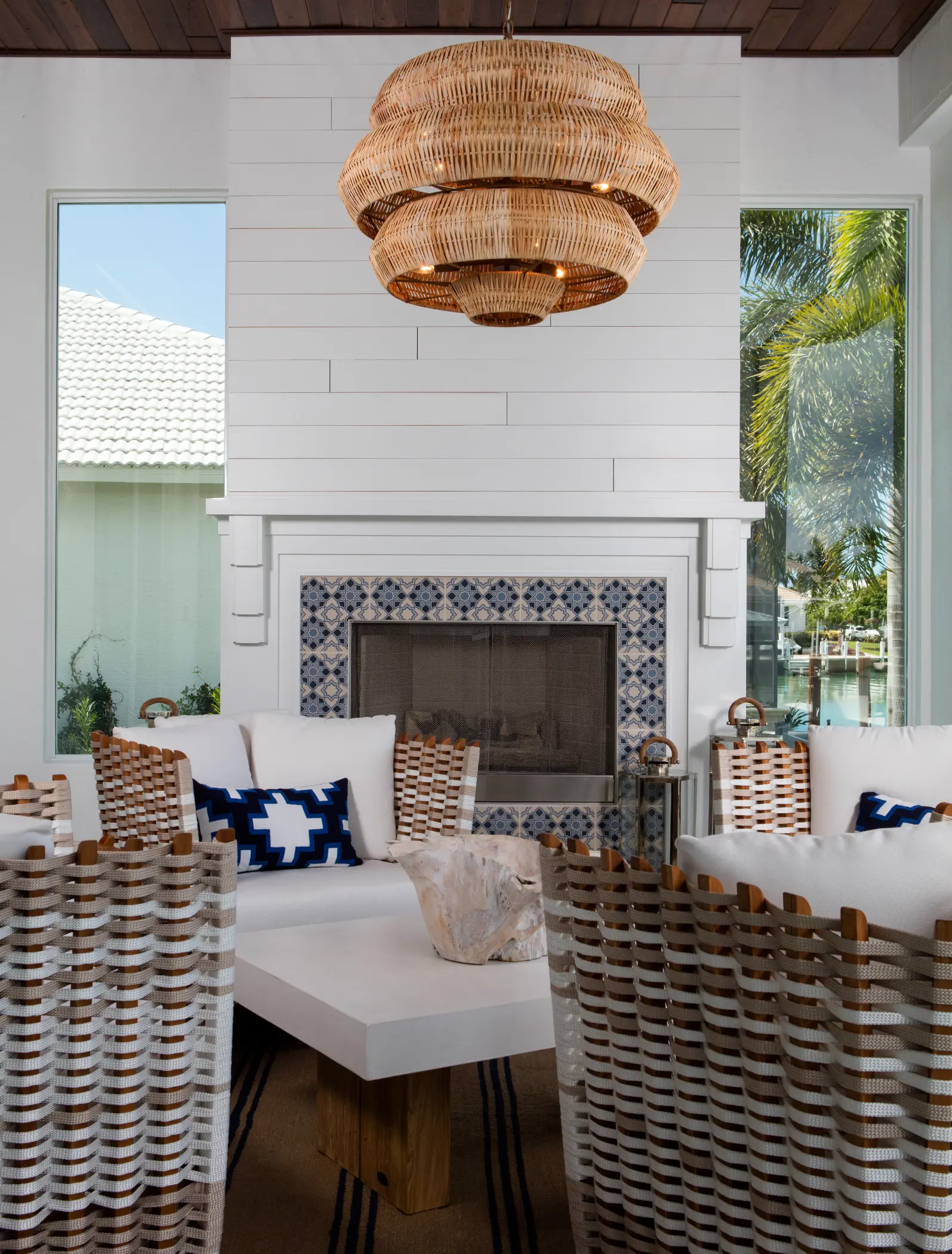 Room with white and wooden furniture, wicker chairs, and a large woven pendant light above.