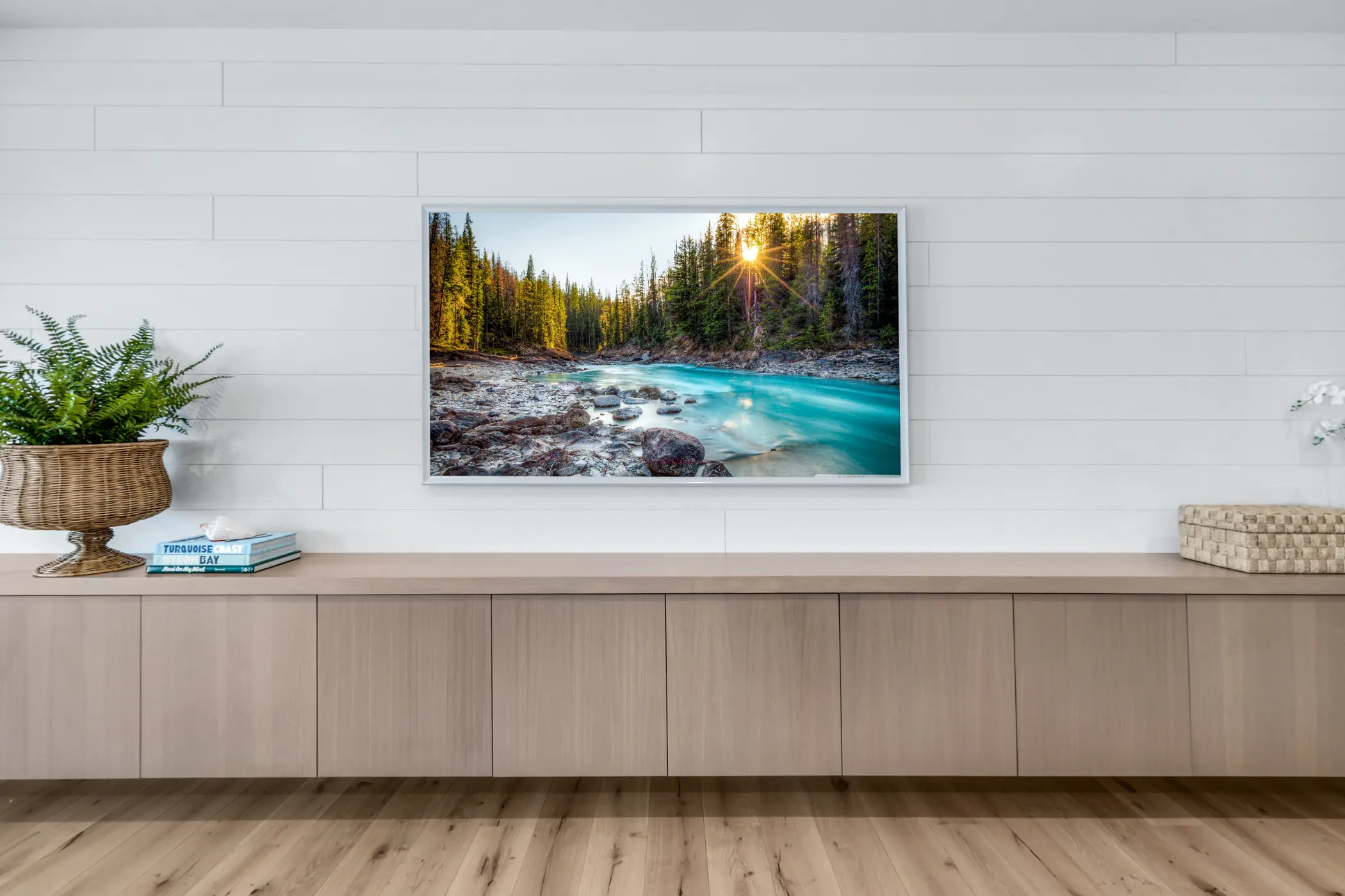 A modern living room with a landscape painting of a river and forest on the wall.