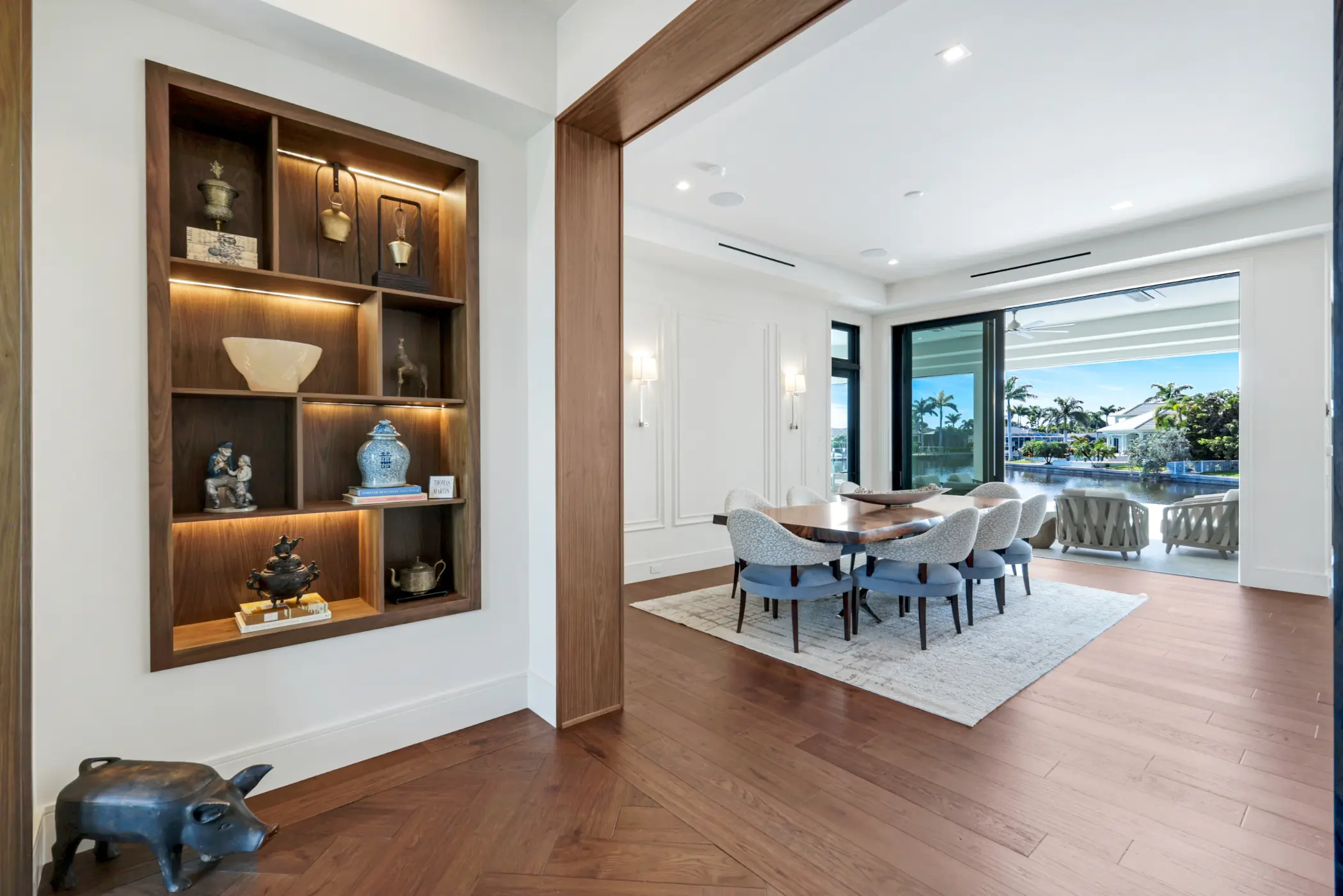 A dining room with a wooden table, eight chairs, and a view of a sunny patio.