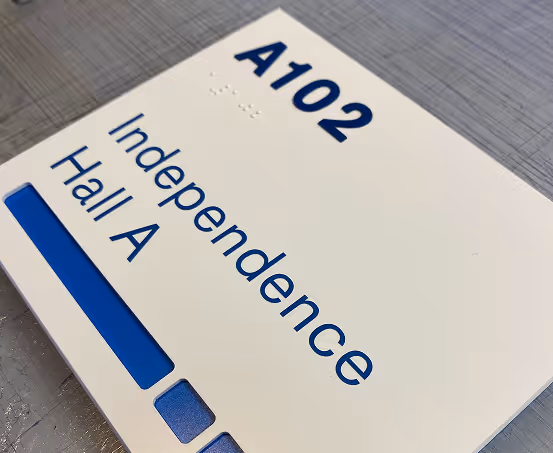 Custom ADA compliant room sign for Independence Hall A102 with tactile text, braille, and blue accent insert