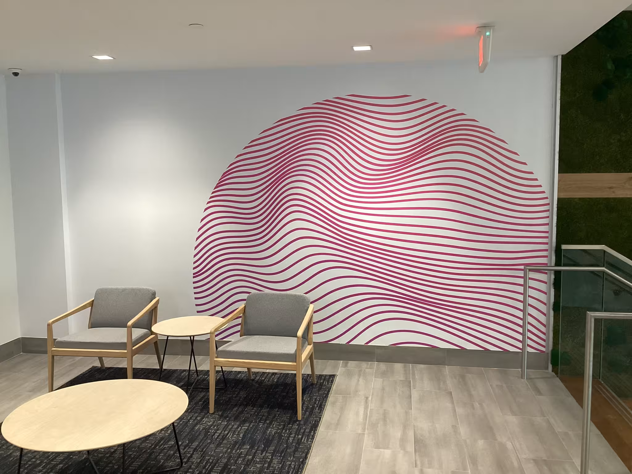 Modern lobby with abstract pink wall graphic of wavy circular lines and minimalist seating area.