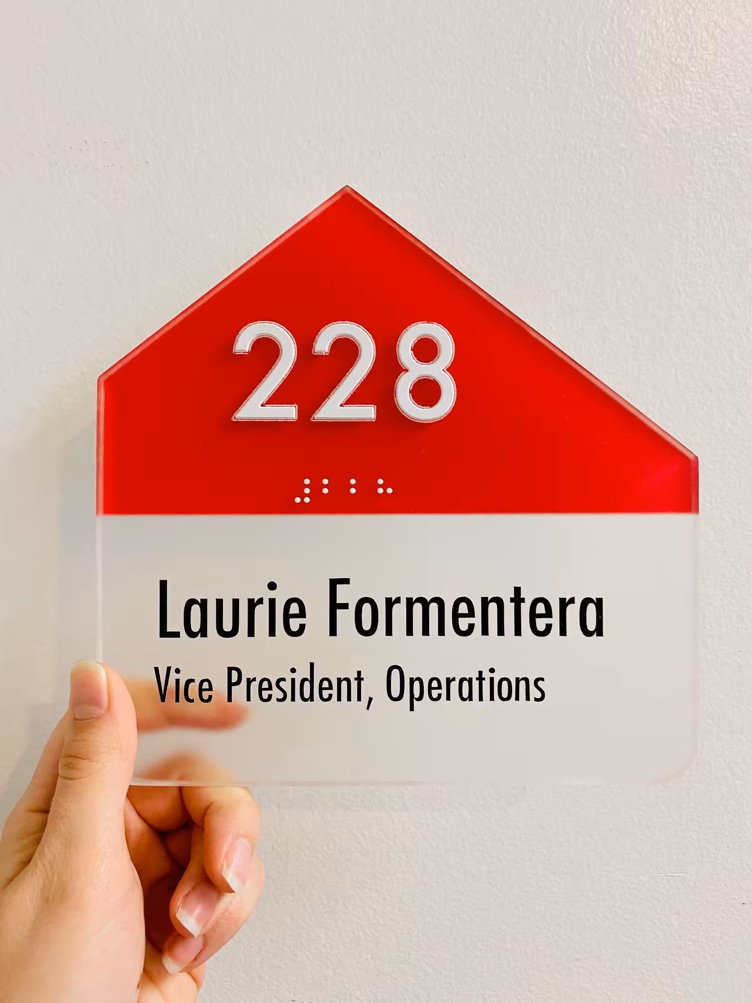 ADA office sign with red triangle top reading ‘228 Laurie Formentera, Vice President, Operations.