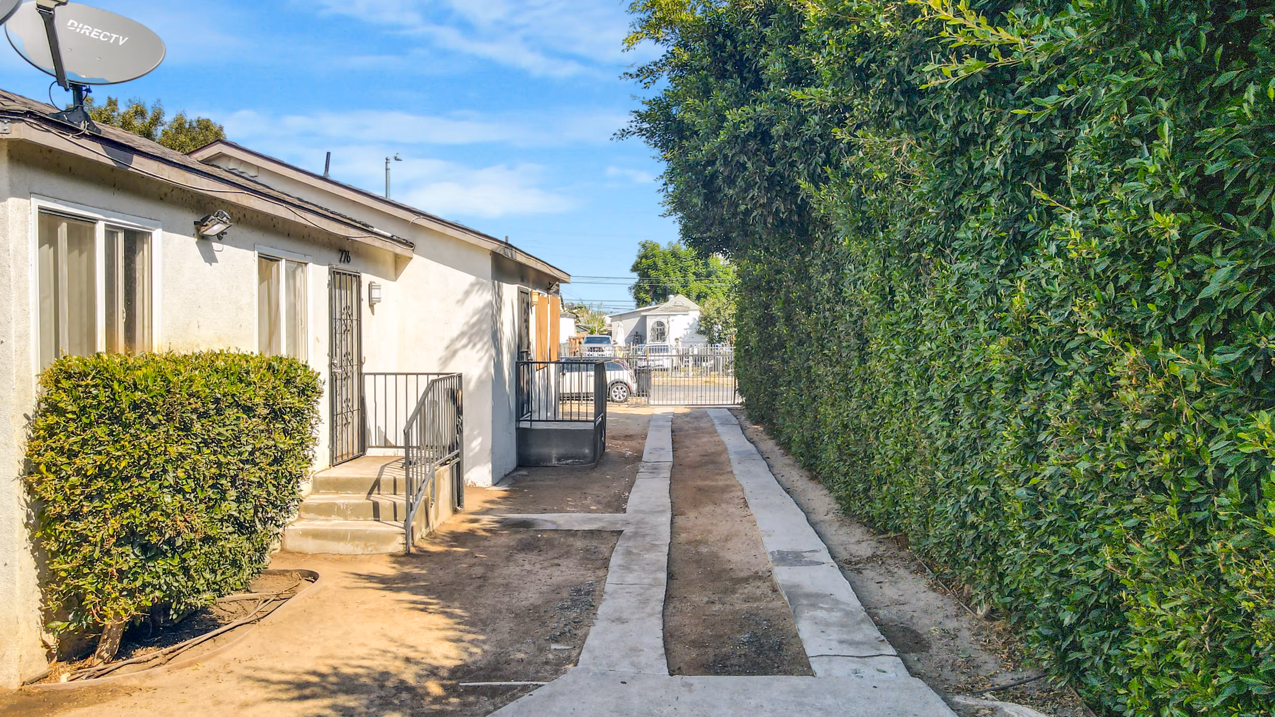 A wide-angle view of the property's exterior, including the driveway and landscaping, located in South Los Angeles