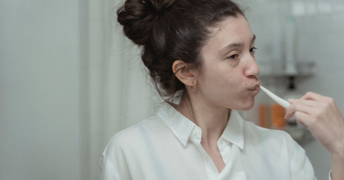Woman brushing her teeth in front of a bathroom mirror