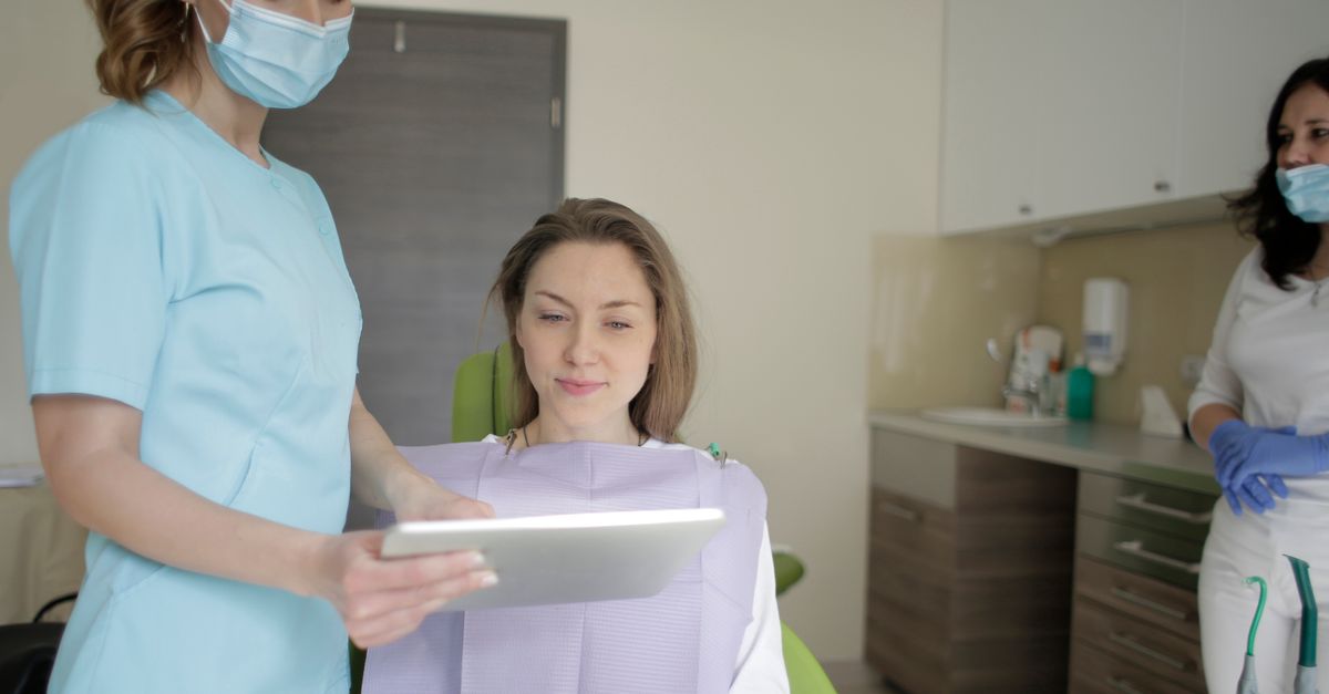 Dental team member showing a woman in the dental chair a treatment plan on a tablet