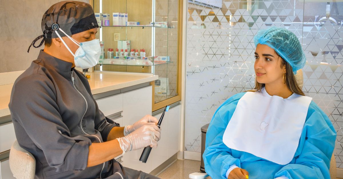 Dentist talking with a woman in a dental chair before an exam