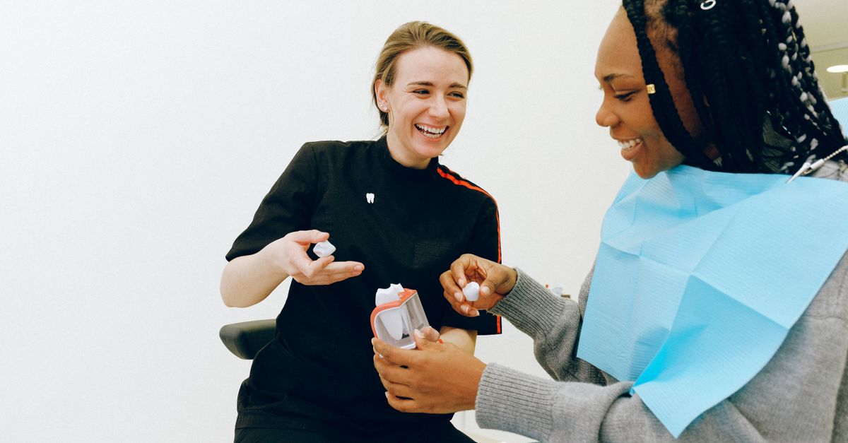 Dentist explaining a treatment plan to a smiling woman in a dental chair