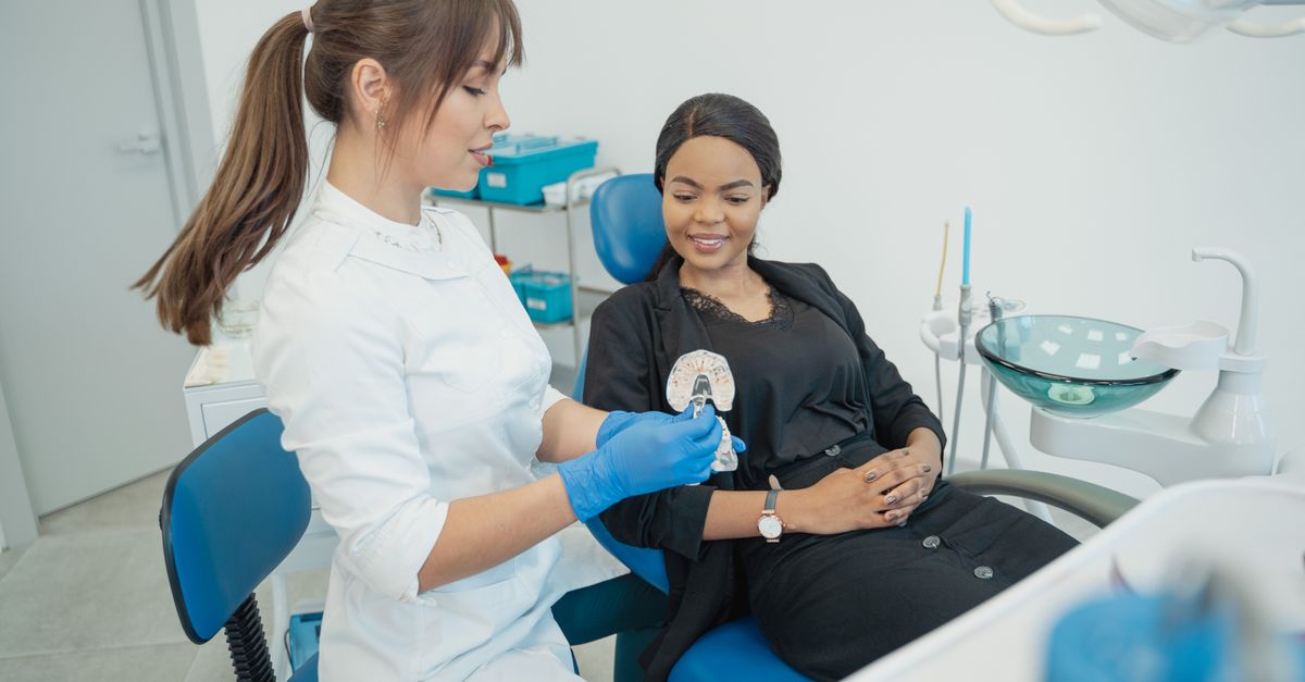 Dentist explaining a treatment plan to a smiling woman in a dental chair