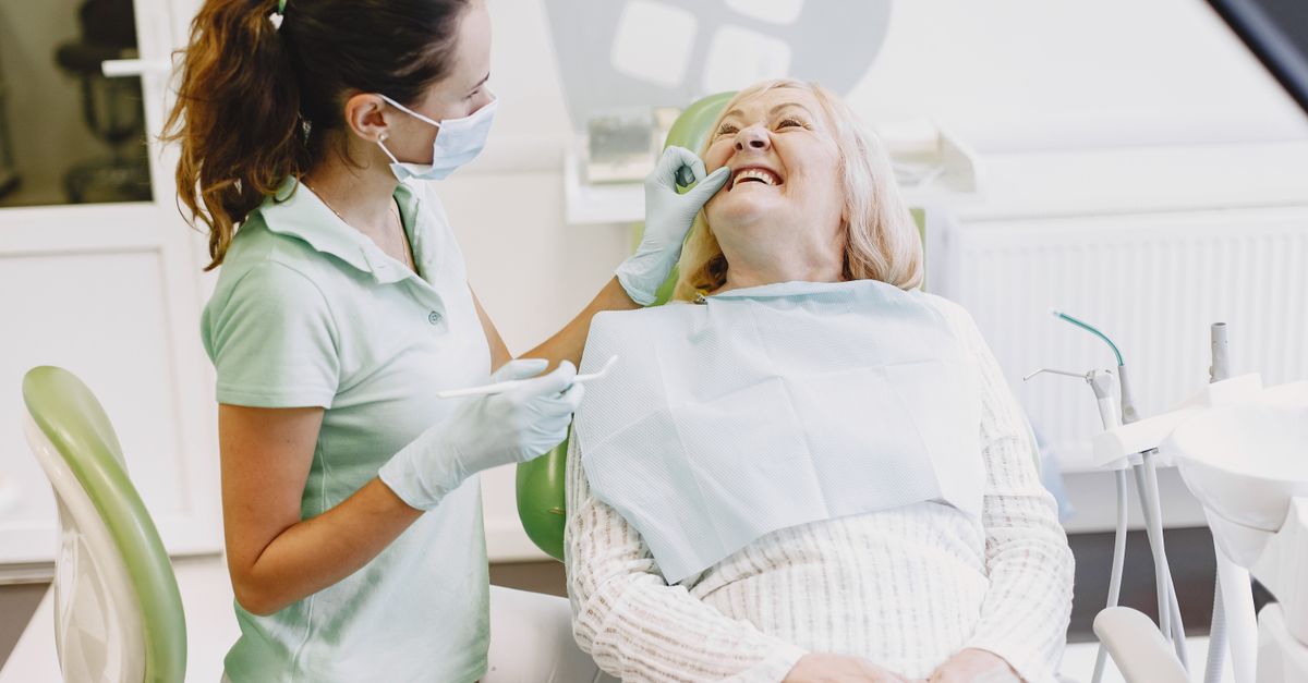 Female dentist examining a smiling older woman in a dental chair