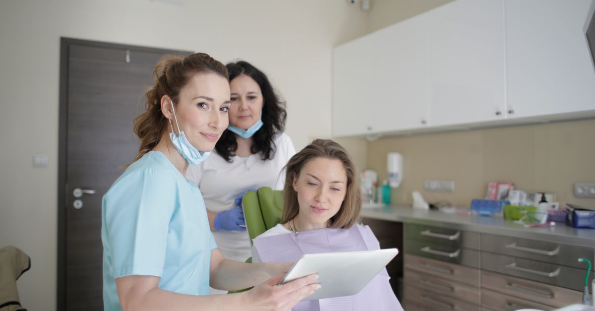 Dental team showing a woman in the dental chair her results on a tablet