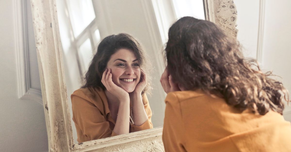 Woman smiling at her reflection in a vintage mirror