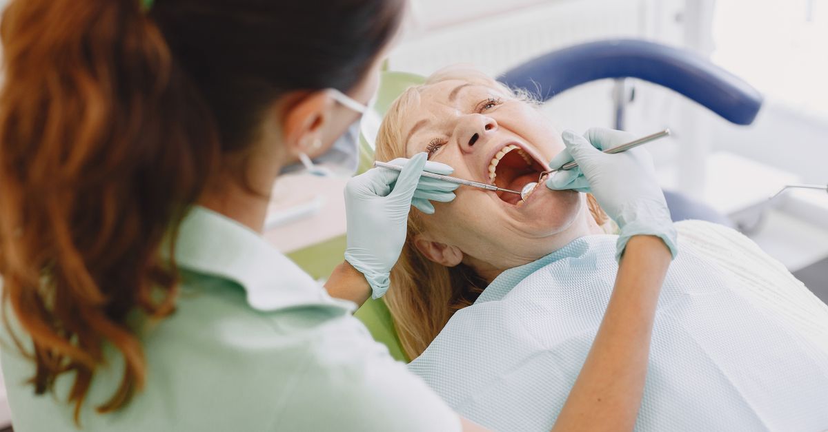 Dentist examining the teeth and gums of a woman in a dental chair
