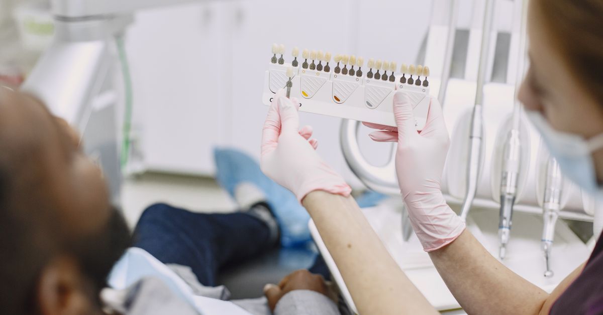 Dental professional holding up a tooth color guide in a dental treatment room