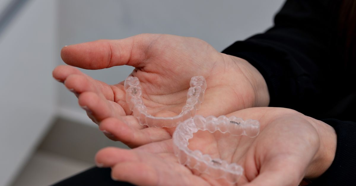 Hands holding a pair of clear aligner trays