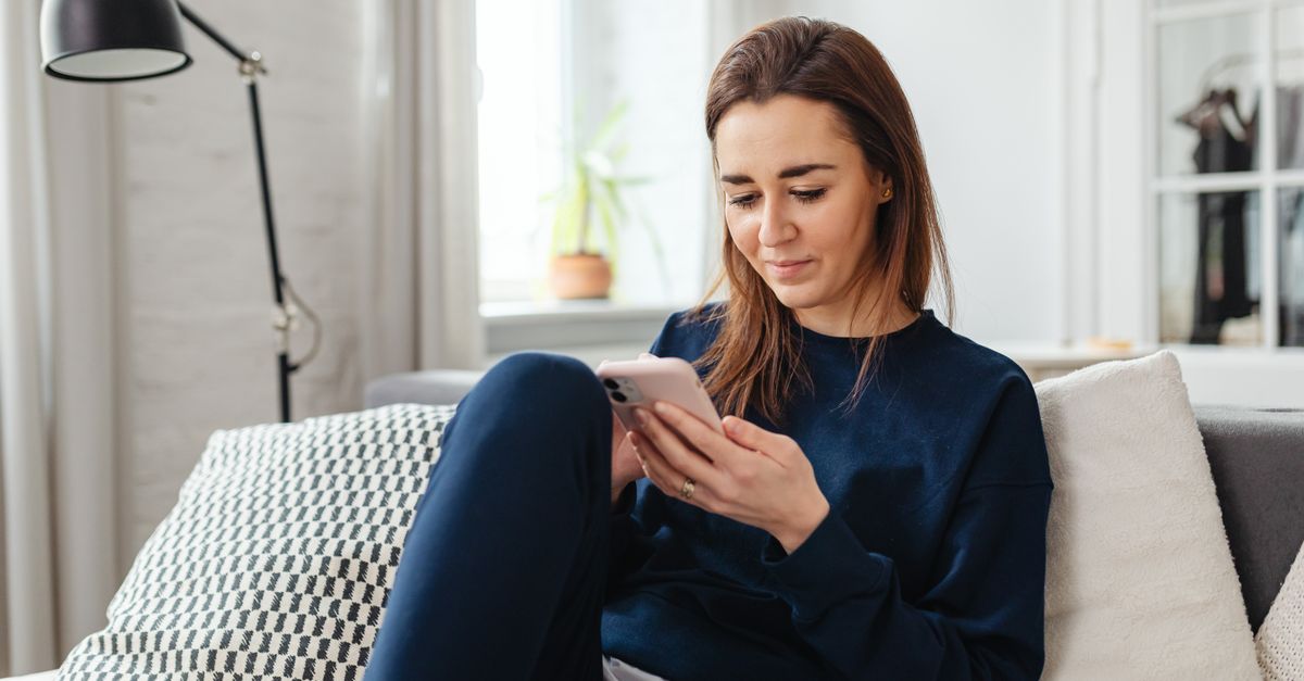 Woman sitting on a couch at home looking at her phone