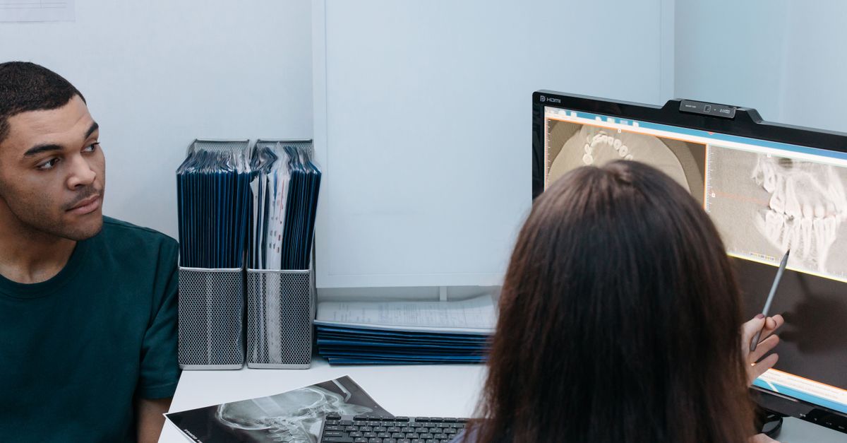 Dentist reviewing dental X-ray images on screen with a man