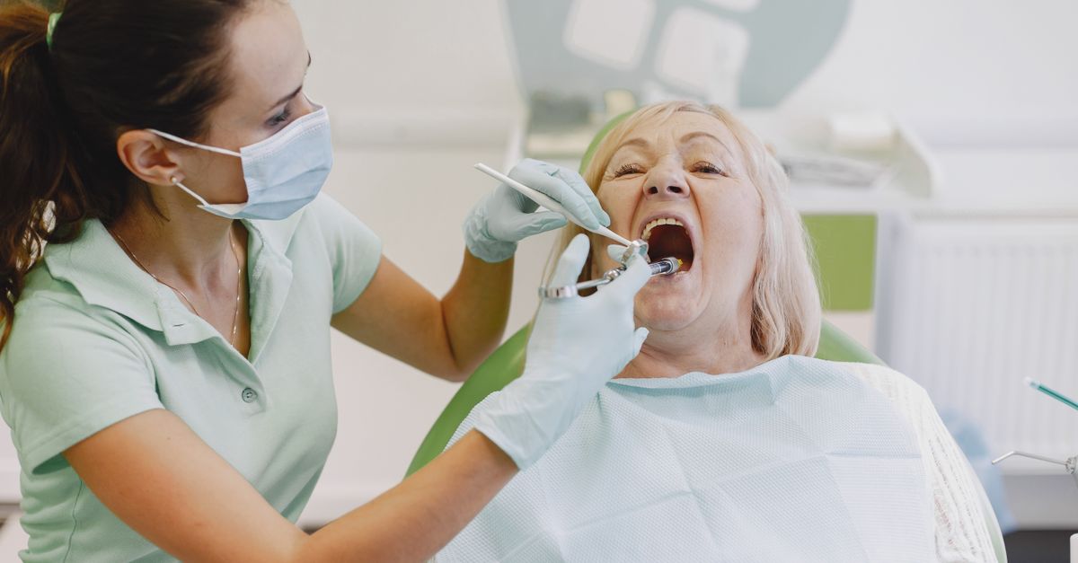 Dentist examining the teeth and gums of an older woman in a dental chair