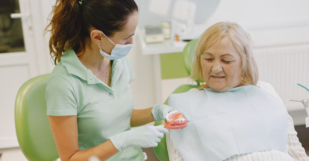 Dentist showing an older woman a dental model while she sits in the dental chair