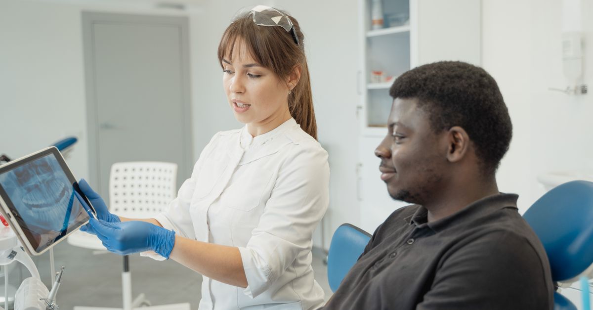 Dentist explaining dental x-rays on a tablet to a man in a dental chair
