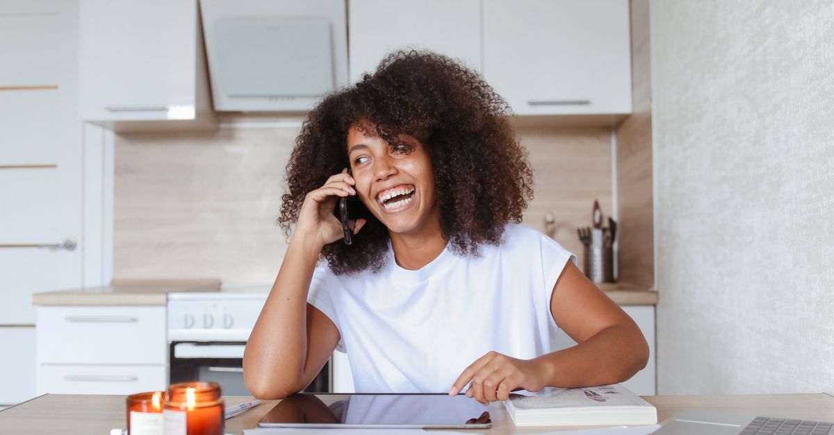 Smiling woman on a phone call at her kitchen table