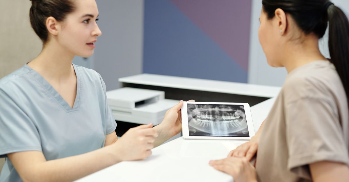 Dentist explaining dental X-ray images on a tablet to a woman