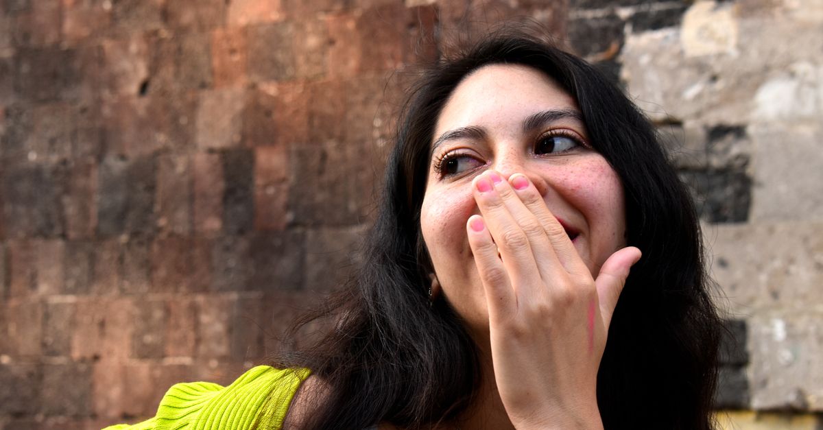 Woman laughing and covering her mouth with her hand